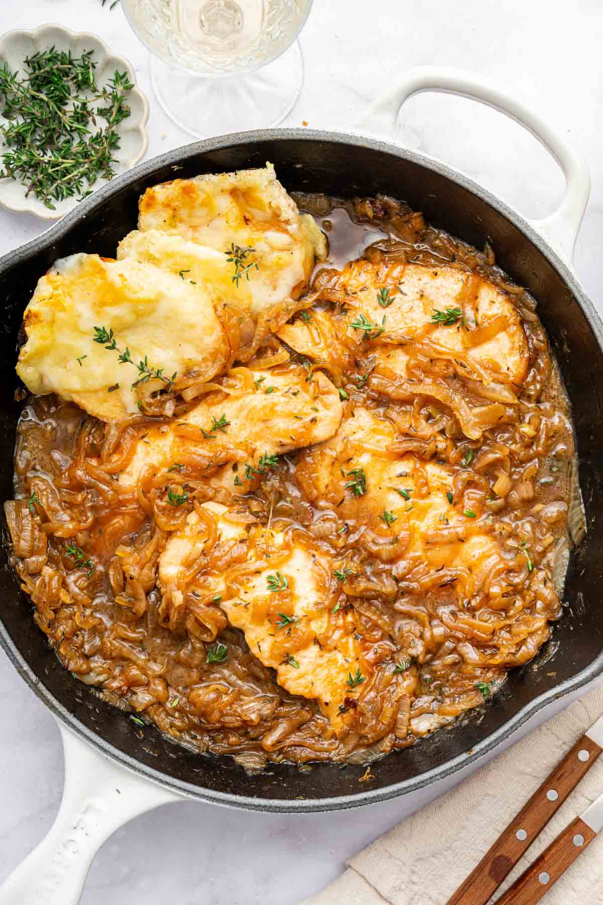 Black skillet with French onion chicken and toasted bread on the side.