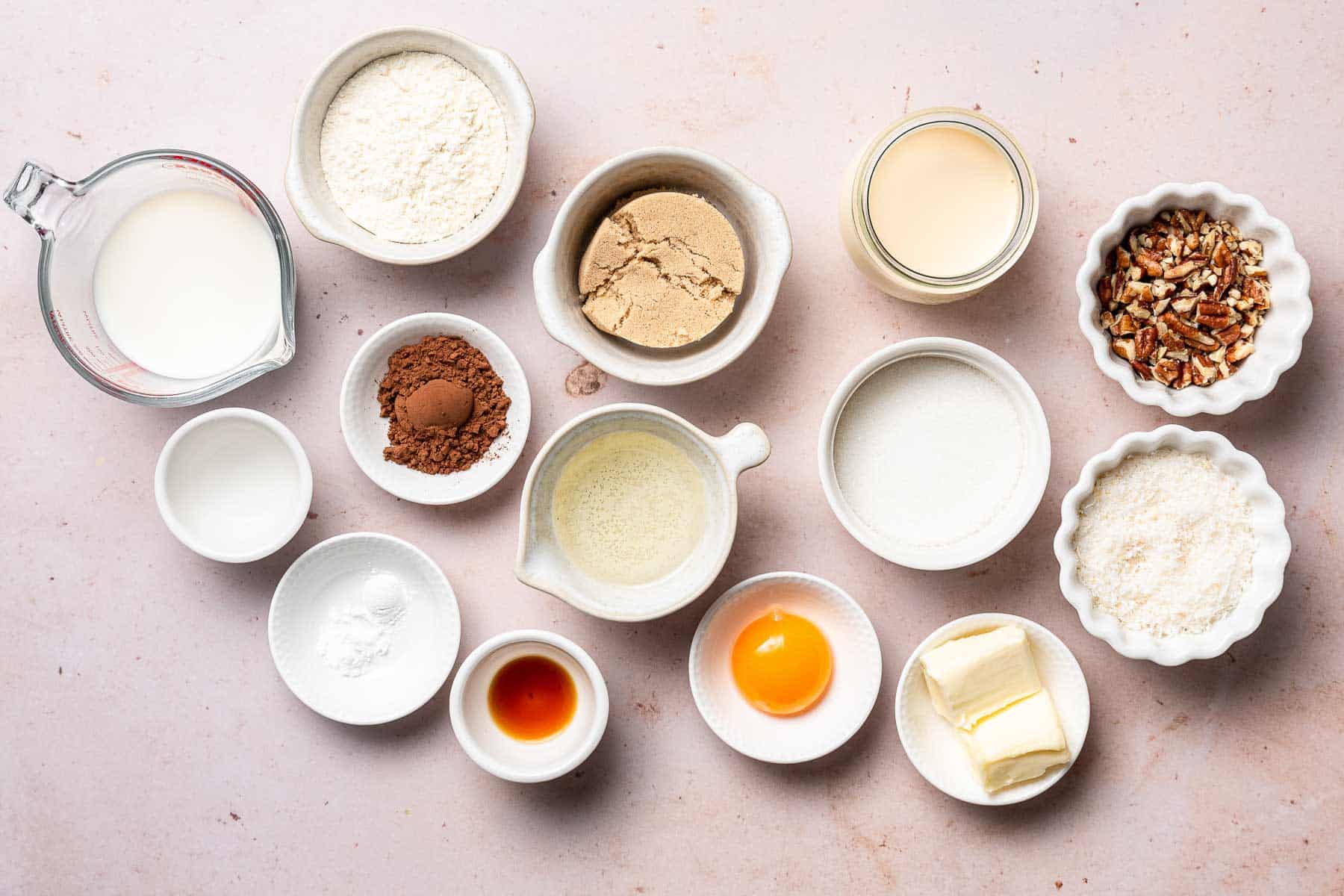 Ingredients for German Chocolate Cupcakes in small bowls on white table.