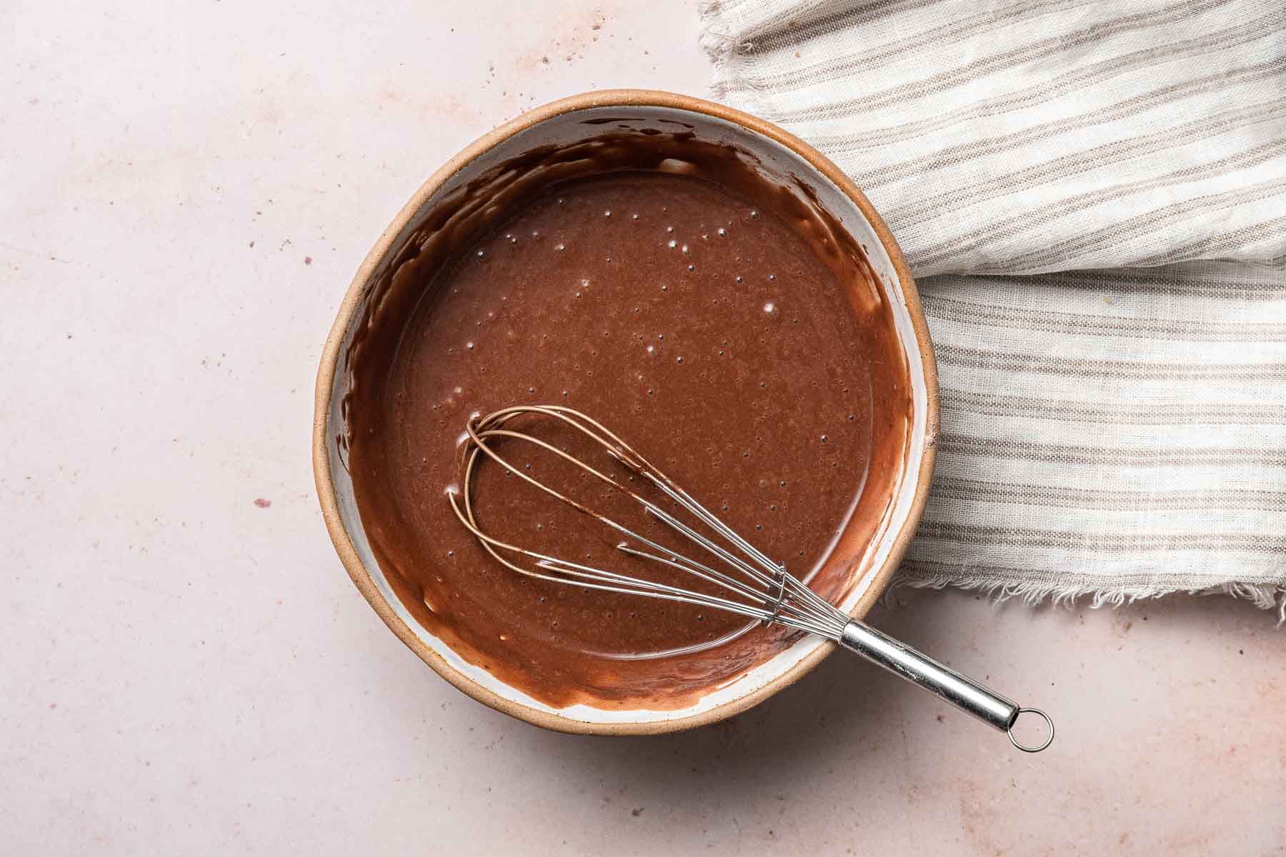 Bowl of raw cupcake batter with whisk.