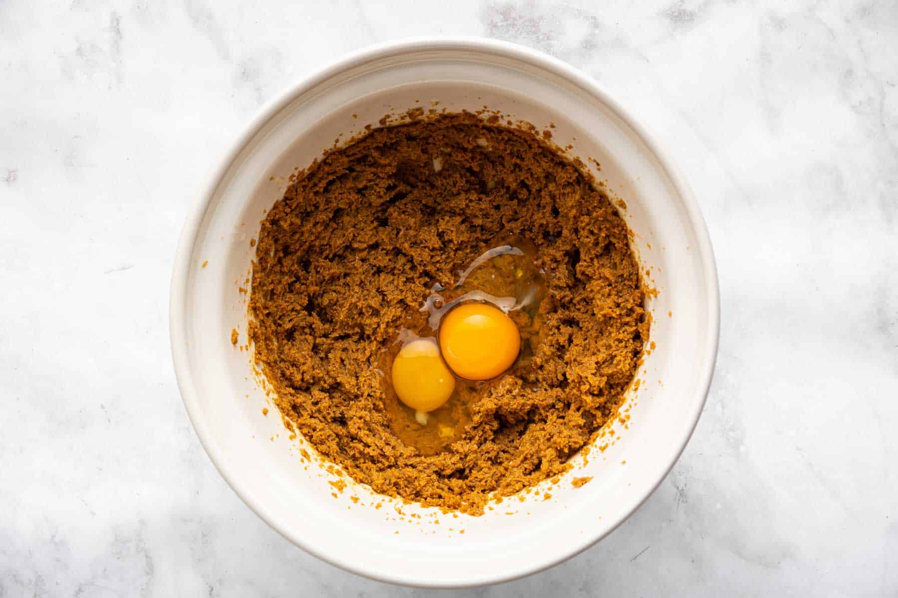 Light brown batter with two raw eggs cracked on top.