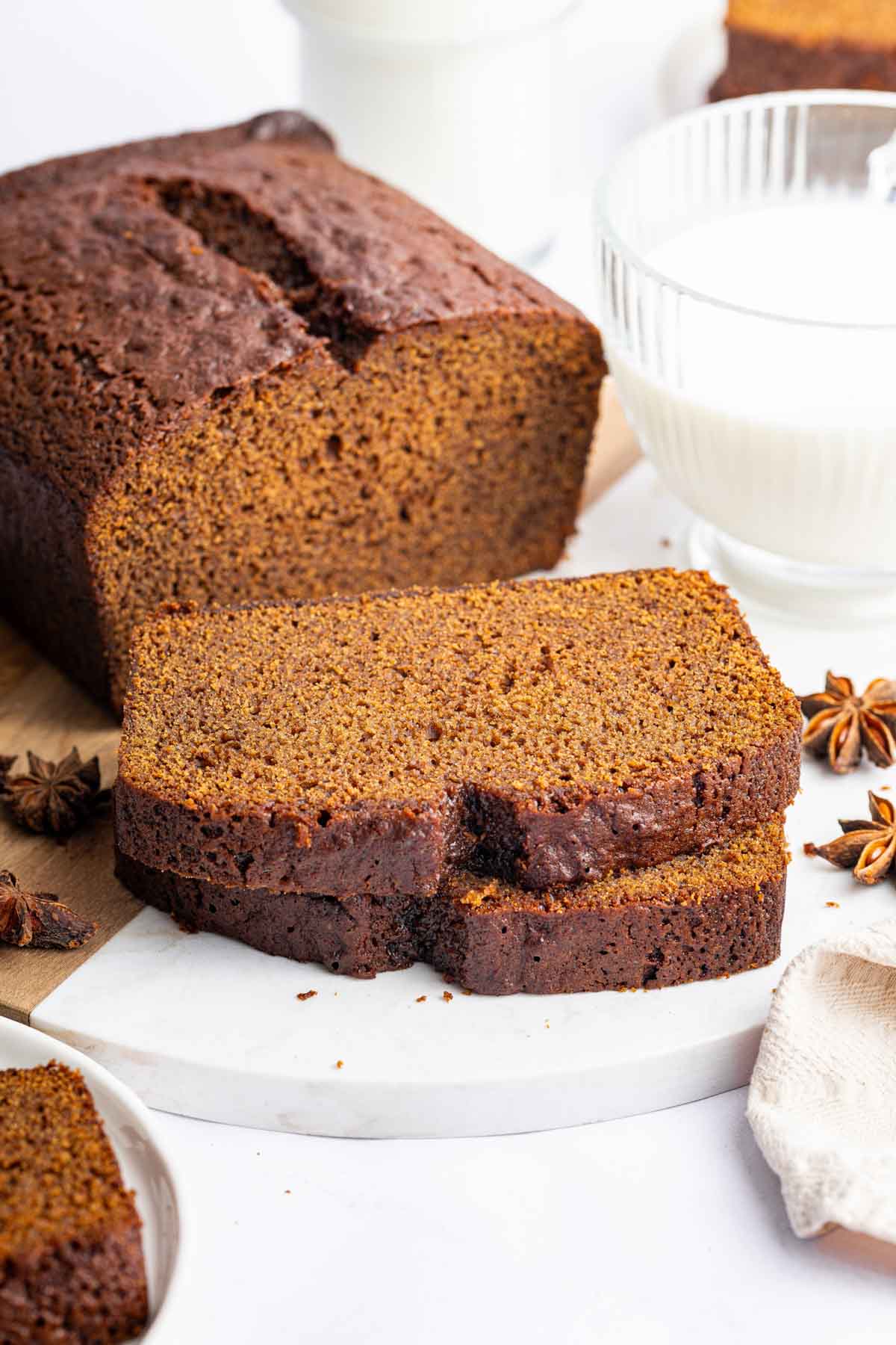 Sliced gingerbread cake loaf on marble circle plate.