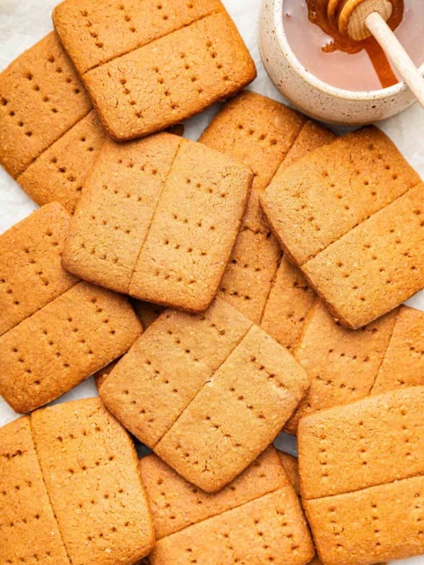 Overhead macro shot of homemade graham crackers with honey pot on side.