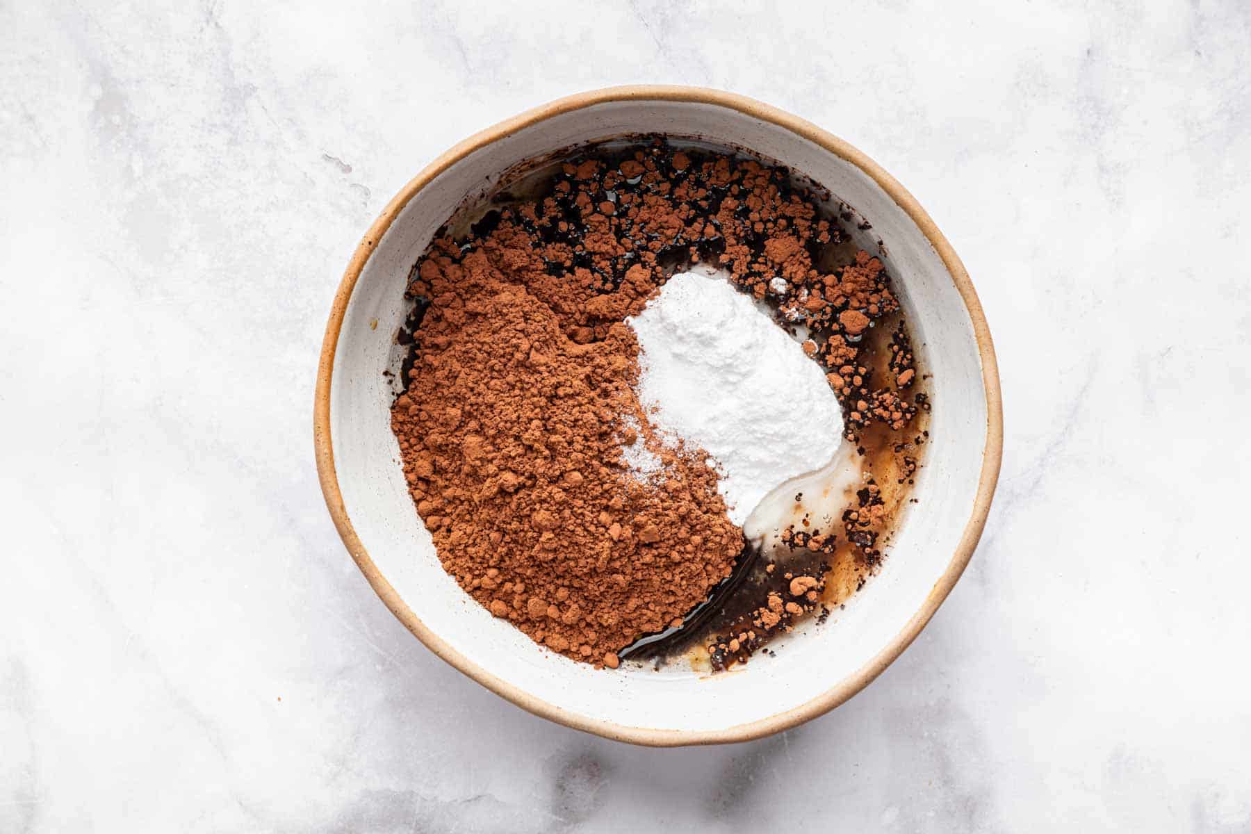 Mixing bowl with cocoa powder, powdered sugar and coconut oil.