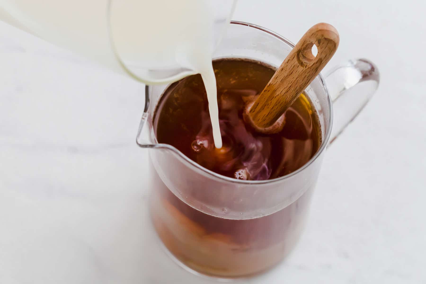Pouring milk into freshly steeped black tea.