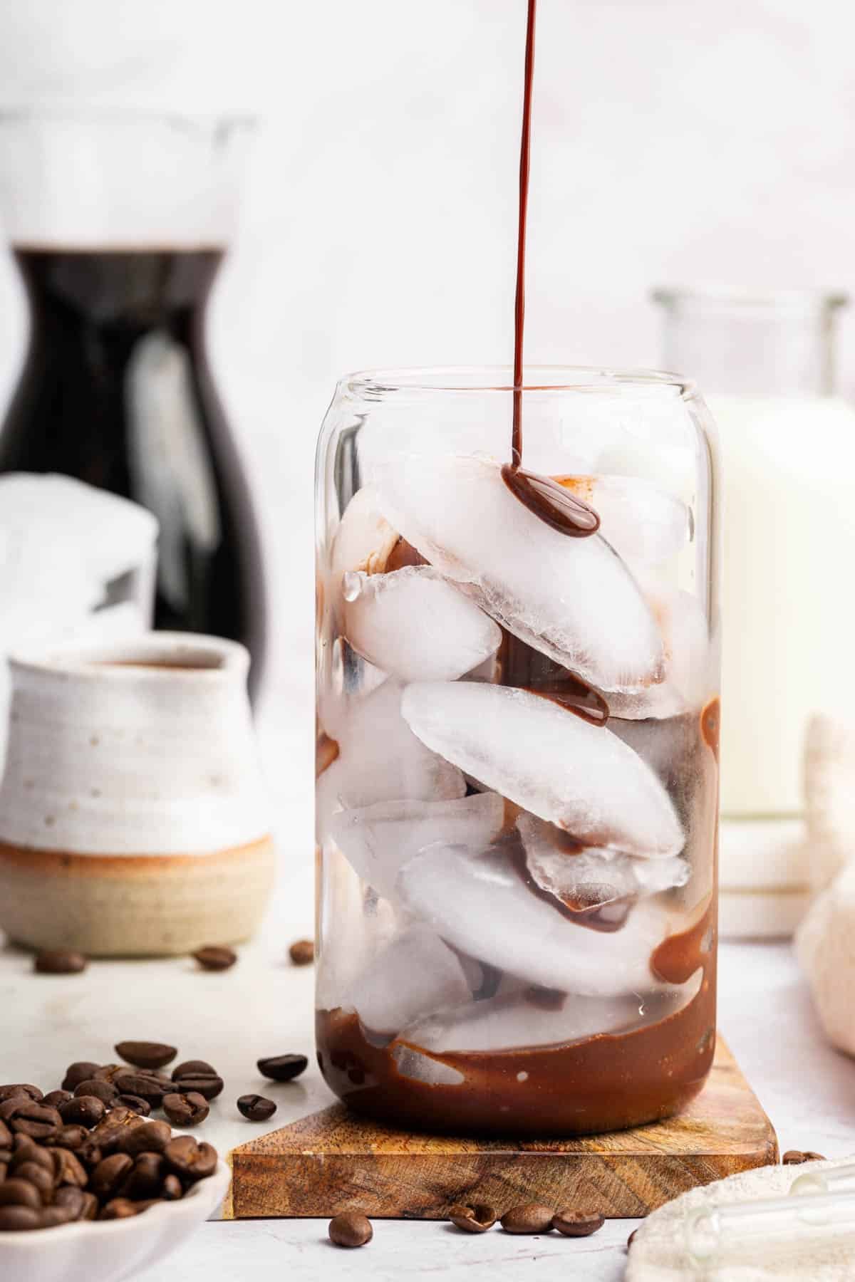 Glass of ice with chocolate sauce being poured on top.