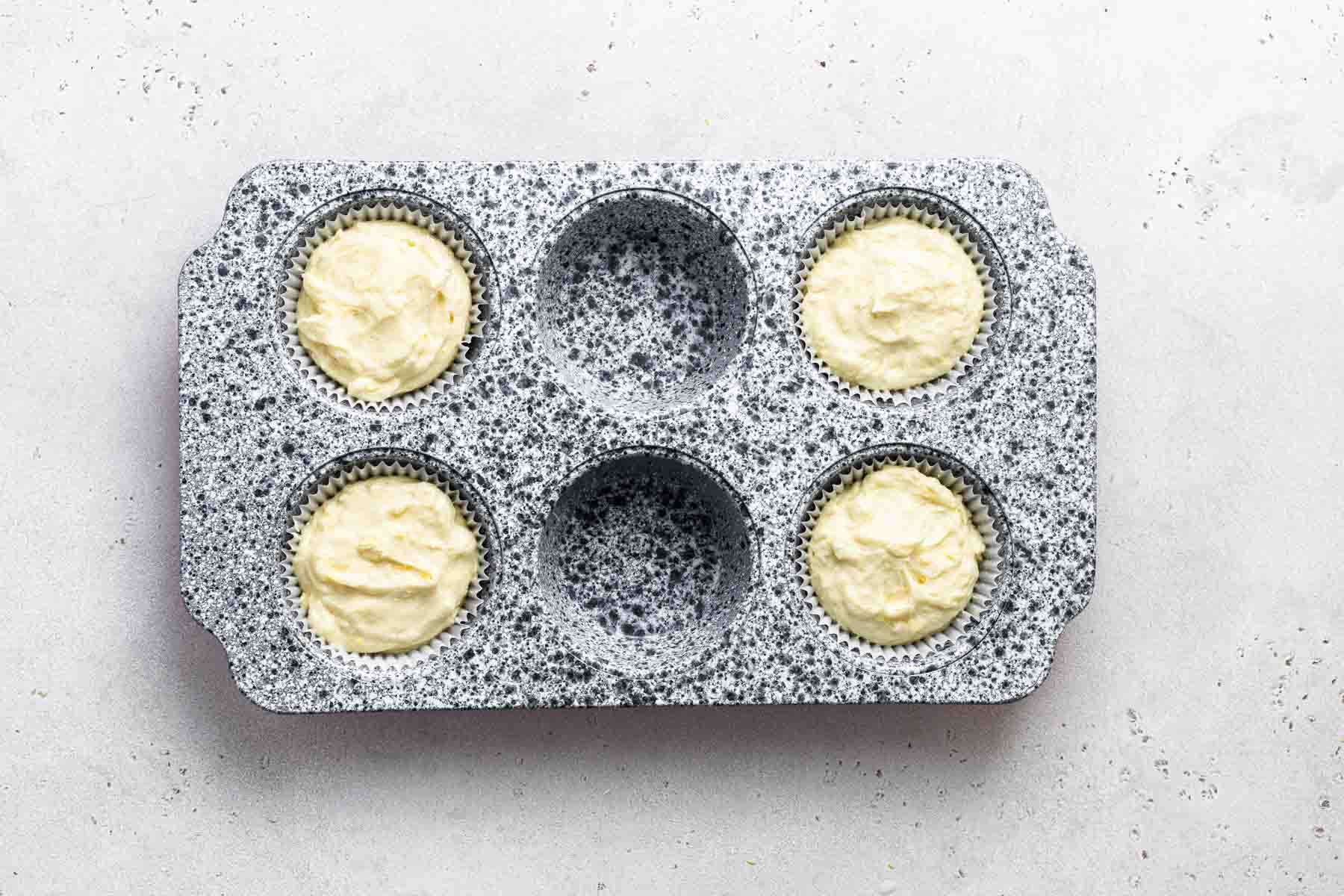 Raw lemon cupcake batter in muffin pan, before baking.