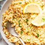 Bowl of lemon orzo garnished with lemon slices and a spoon.