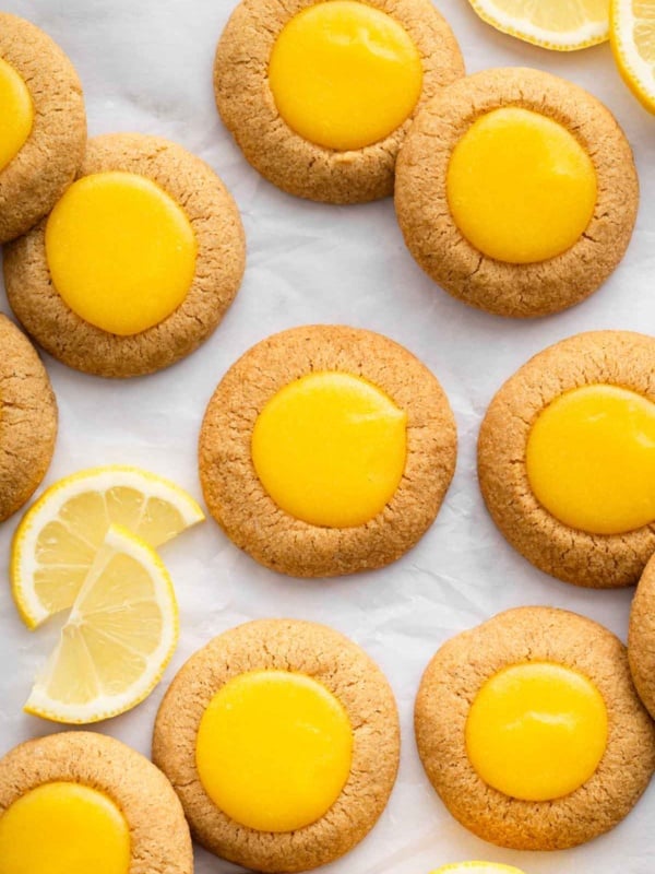 Bright yellow lemon thumbprint cookies on parchment paper.