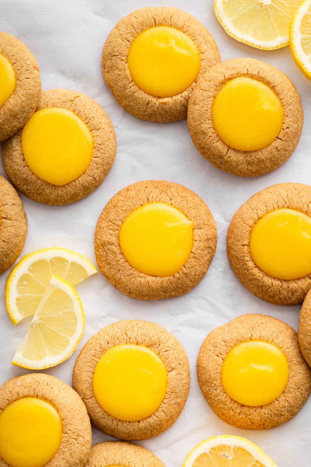 Bright yellow lemon thumbprint cookies on parchment paper.