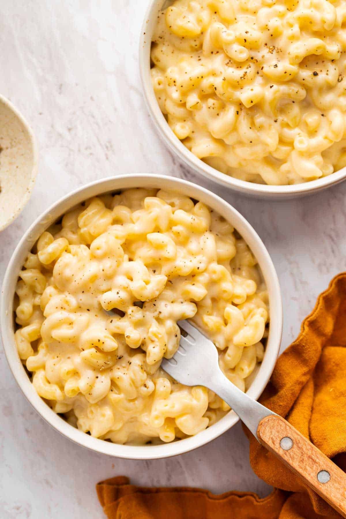 Two portions of macaroni in cheese in two bowls.