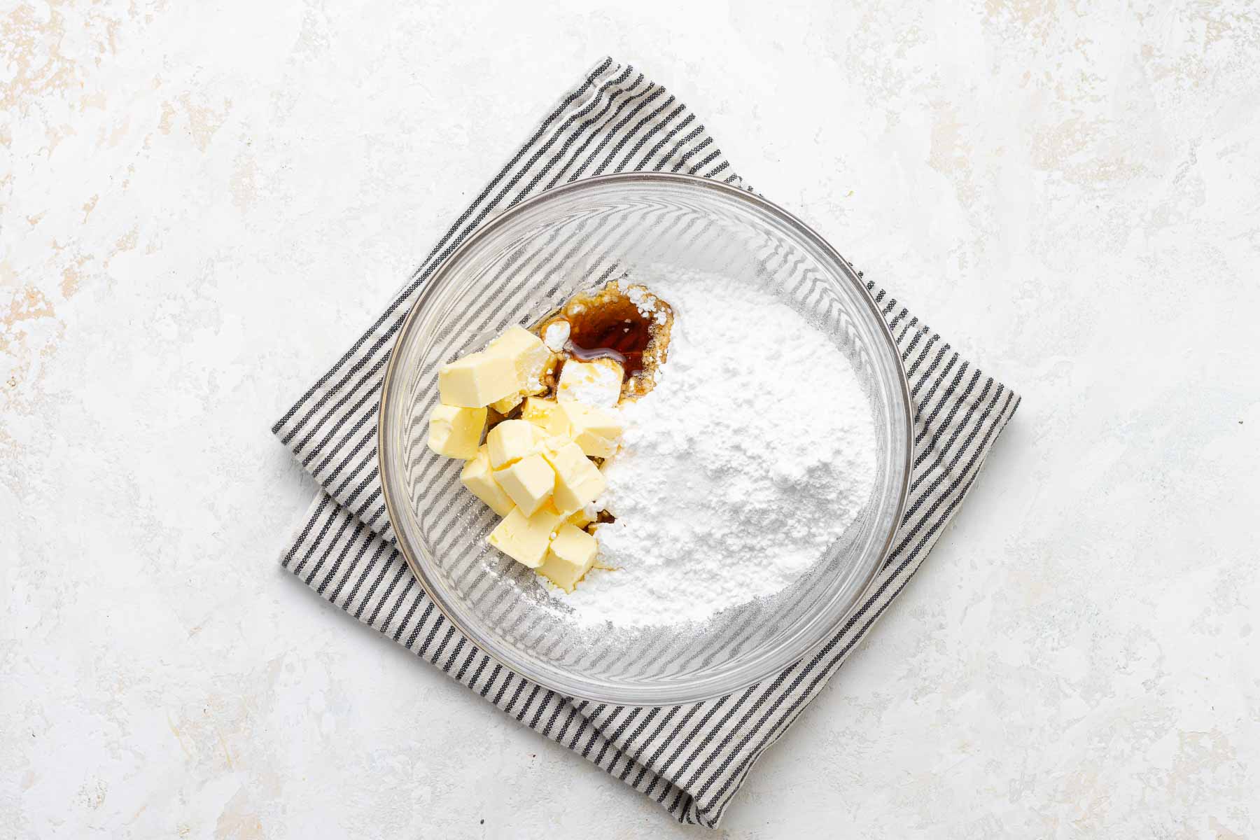 Making maple buttercream frosting in a clear bowl.