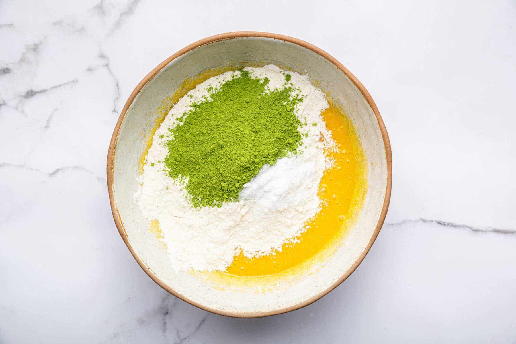 Yellow batter with flour and green matcha powder on top.