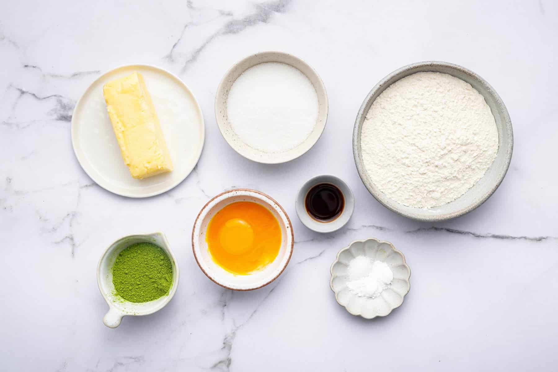 Bowls with flour, sugar, tea powder, and a stick of butter.