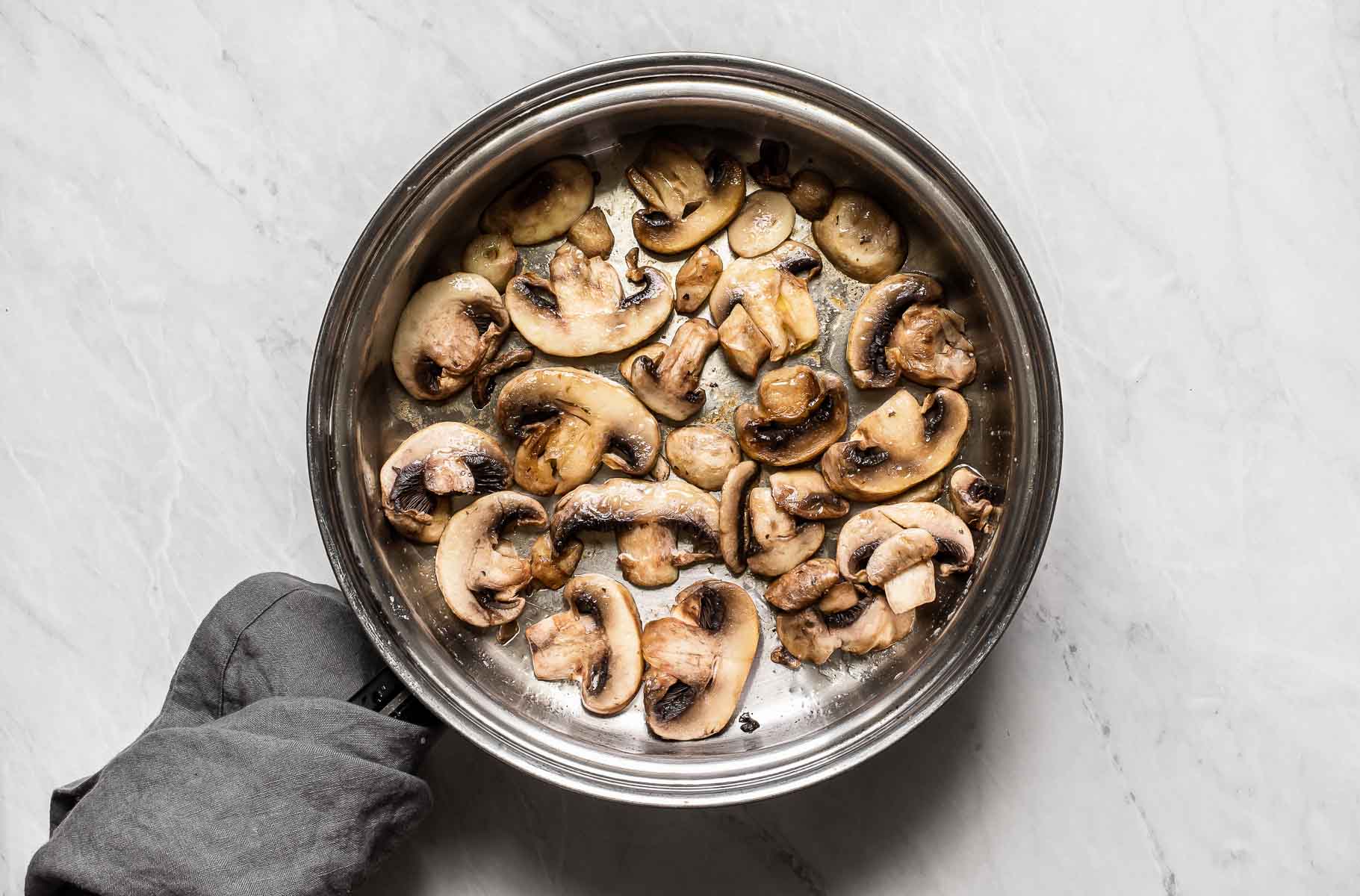Mushrooms cooking in a skillet.