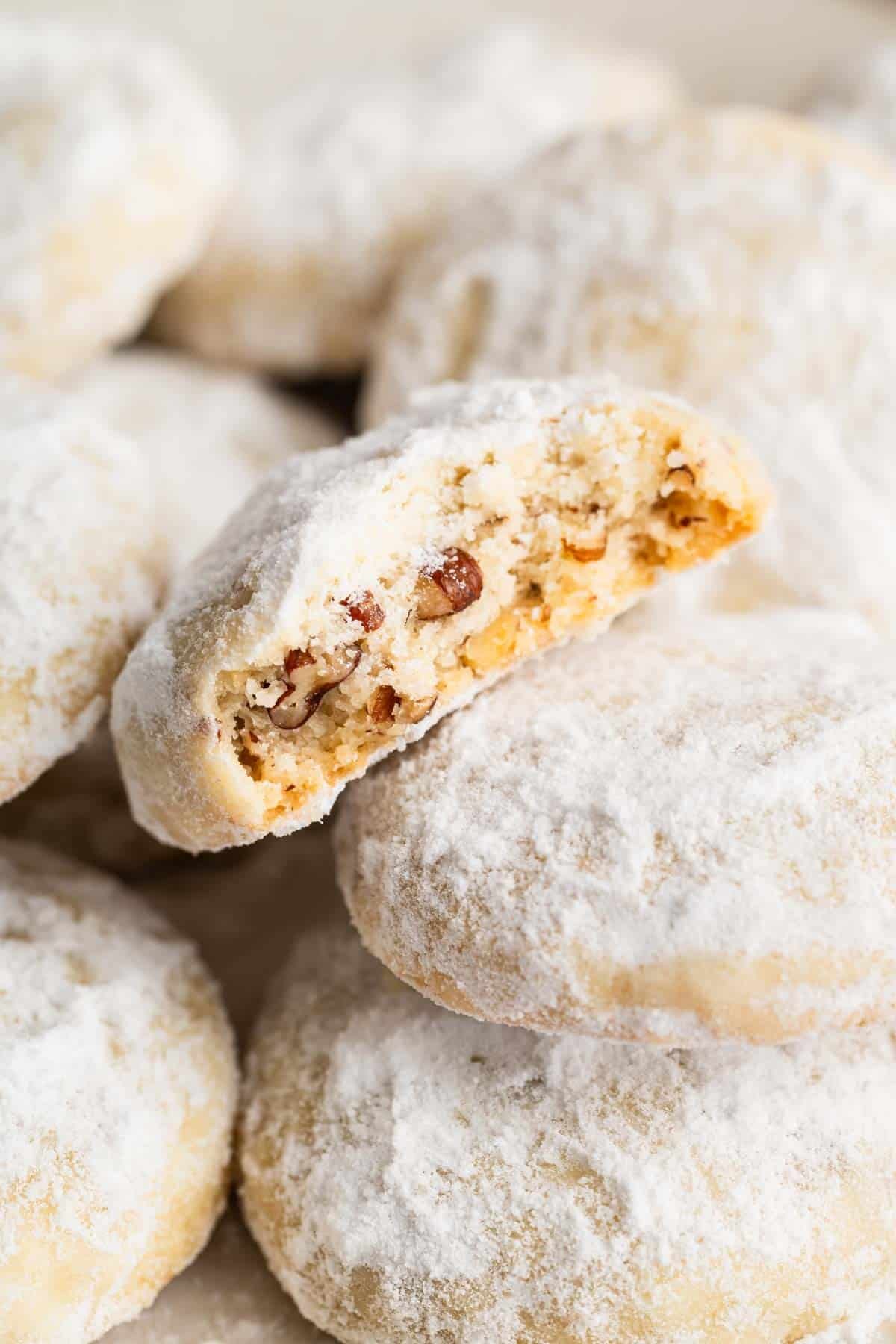 Pile of Mexican wedding cookies with bite missing from top one.