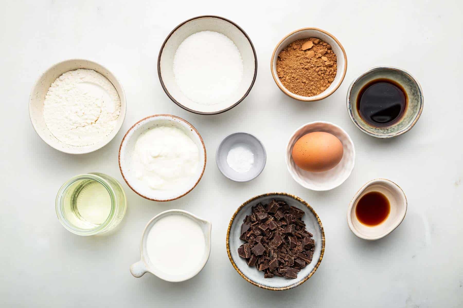 White bowls with cocoa powder, sugar, egg, oil and vanilla.