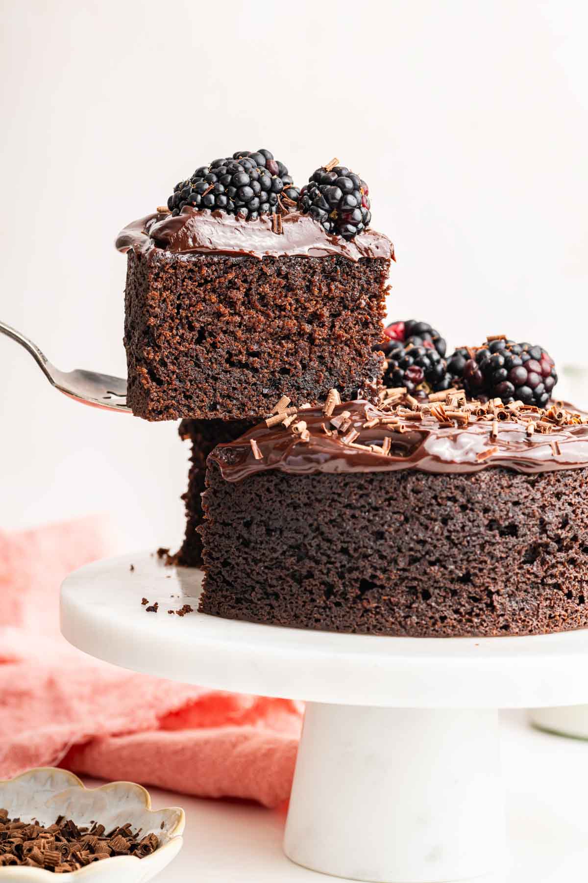 Small spatula removing a small slice of cake from a larger cake.