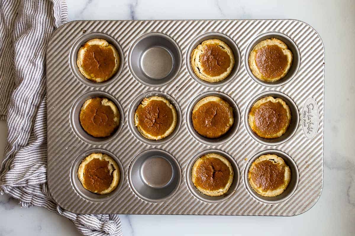 Muffin pan with orange custard bite-size desserts cooked in it.