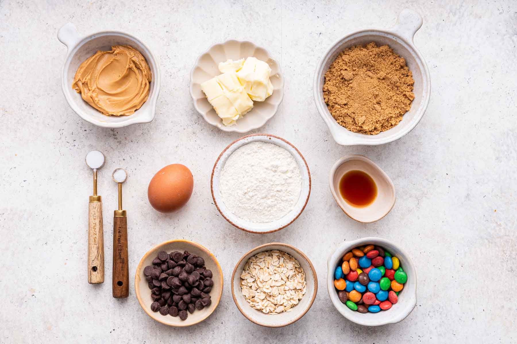 Small bowls of ingredients for monster cookies on white counter.