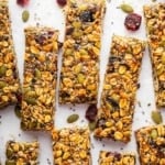 No bake nut free granola bars on a table with cranberries and pipits.