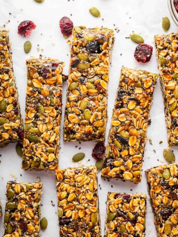 No bake nut free granola bars on a table with cranberries and pipits.