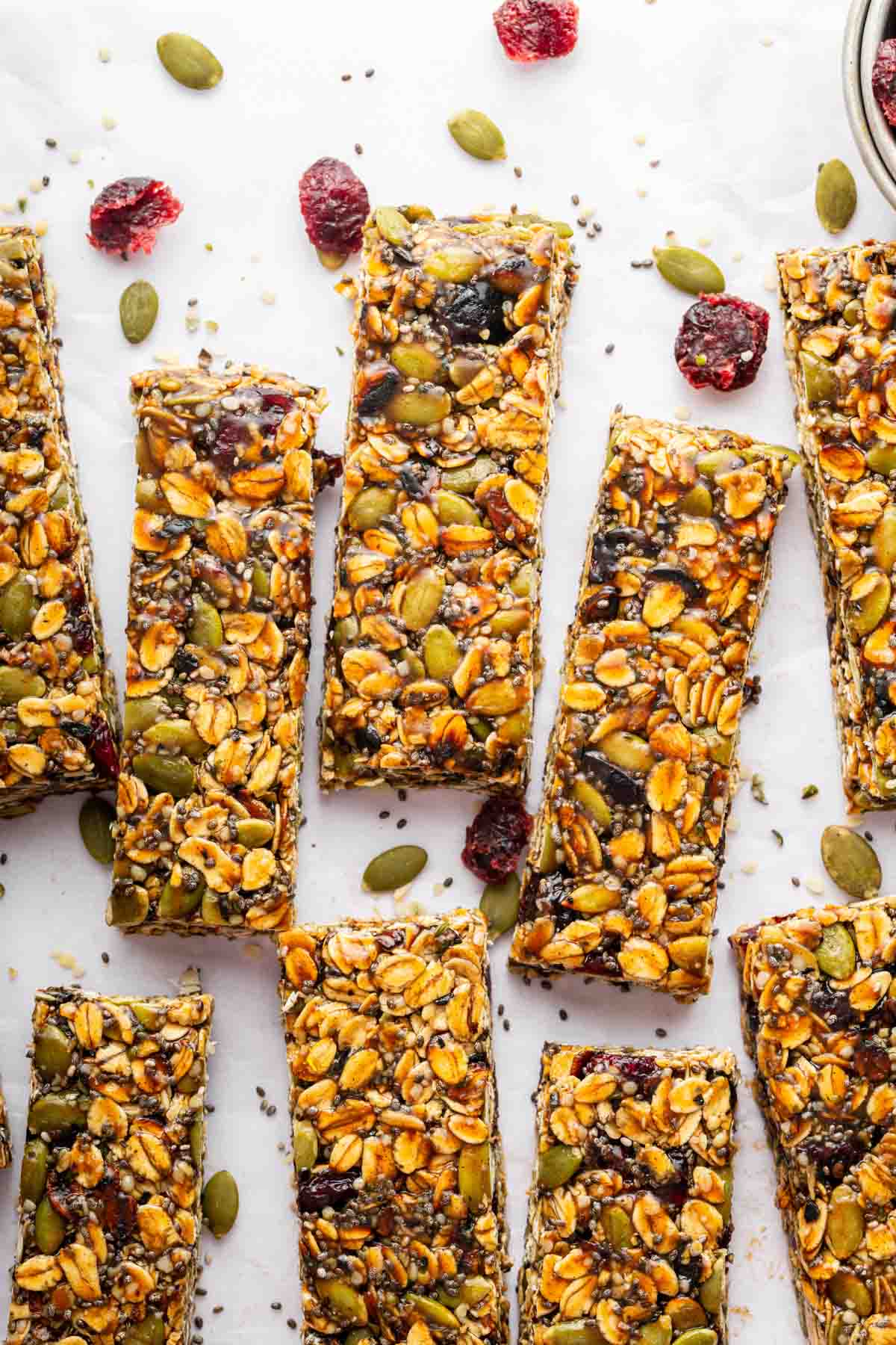 No bake nut free granola bars on a table with cranberries and pipits.