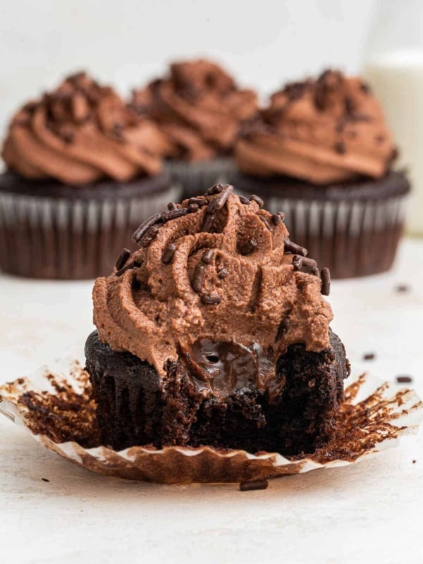 Close up shot of chocolate cupcake cut in half with chocolate center and swirled chocolate frosting.