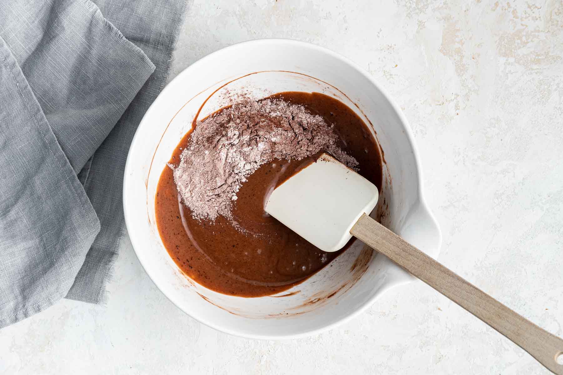 Stirring dry ingredients into wet chocolate batter.