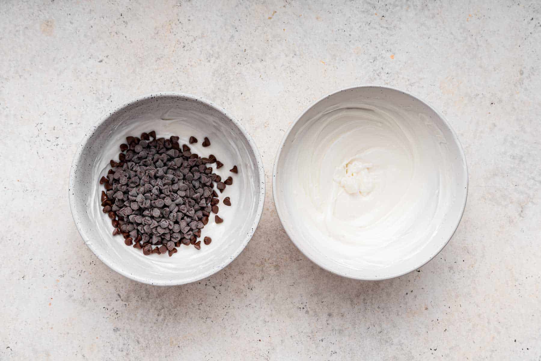 Two bowls side by side, one with melted white chocolate and the other with mini chocolate chips.