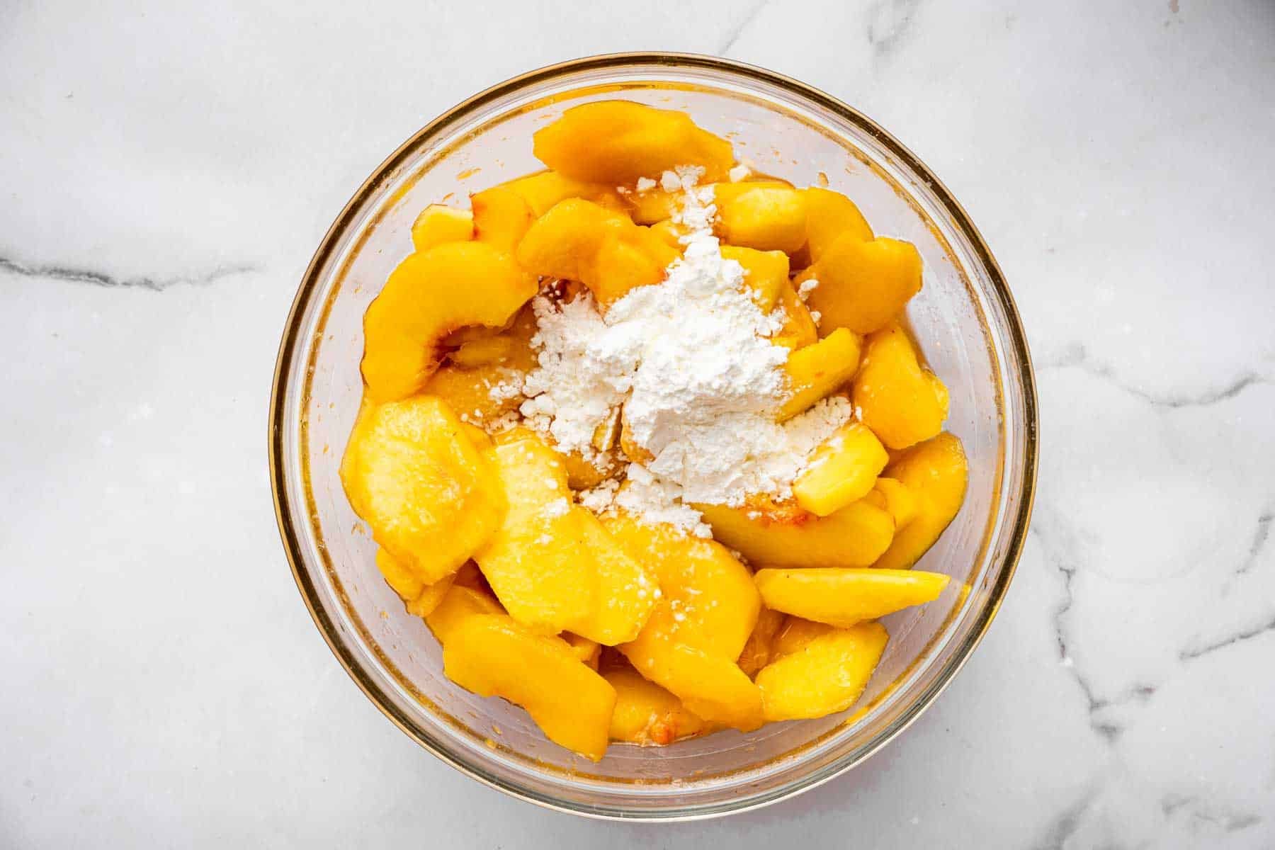 Marinated sliced peaches with cornstarch sprinkled on top.