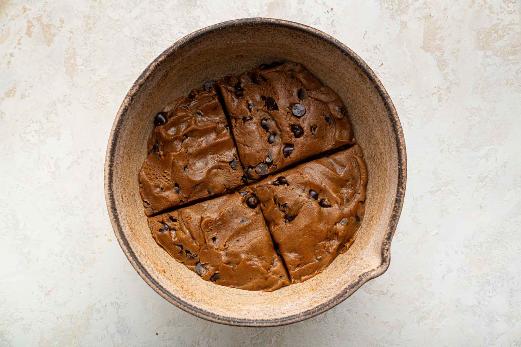 Cookie dough pressed flat in a bowl, and quartered by eye.