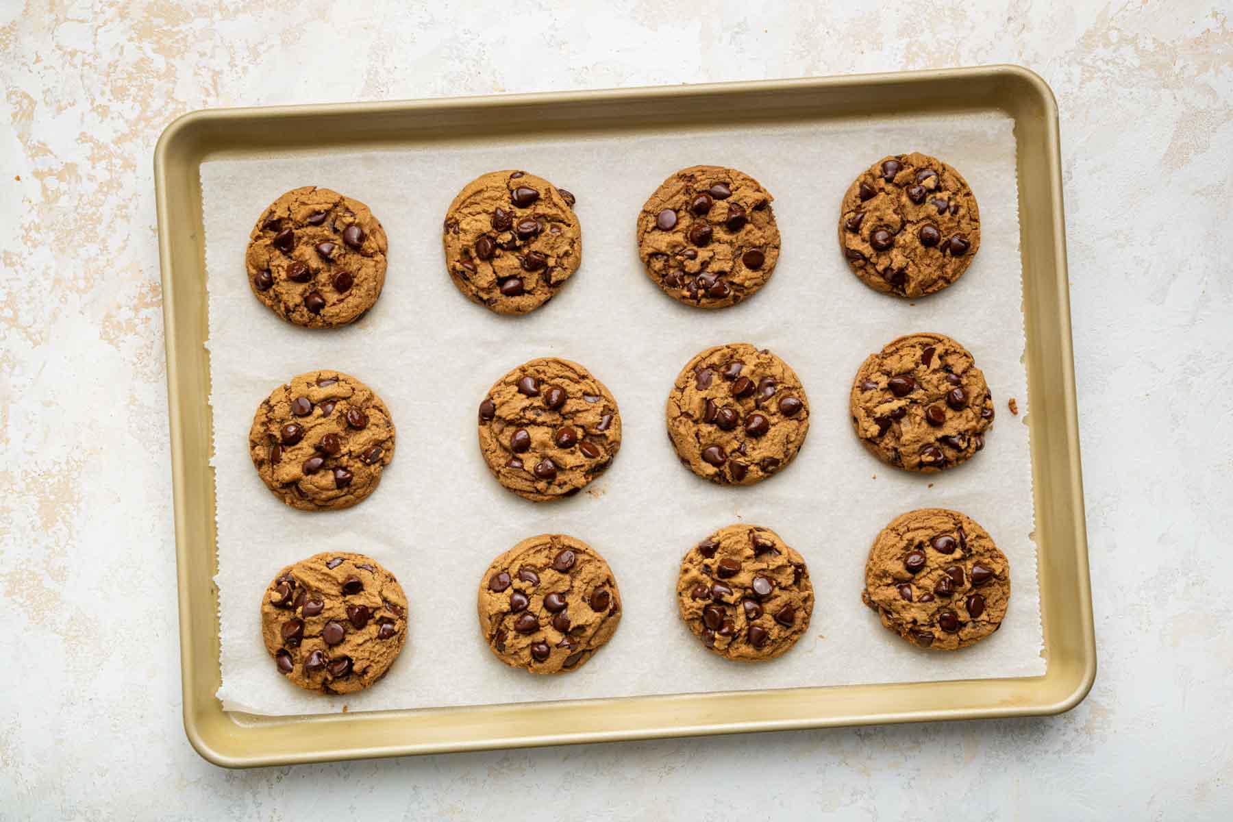 One dozen peanut butter chocolate chip cookies on a baking sheet.