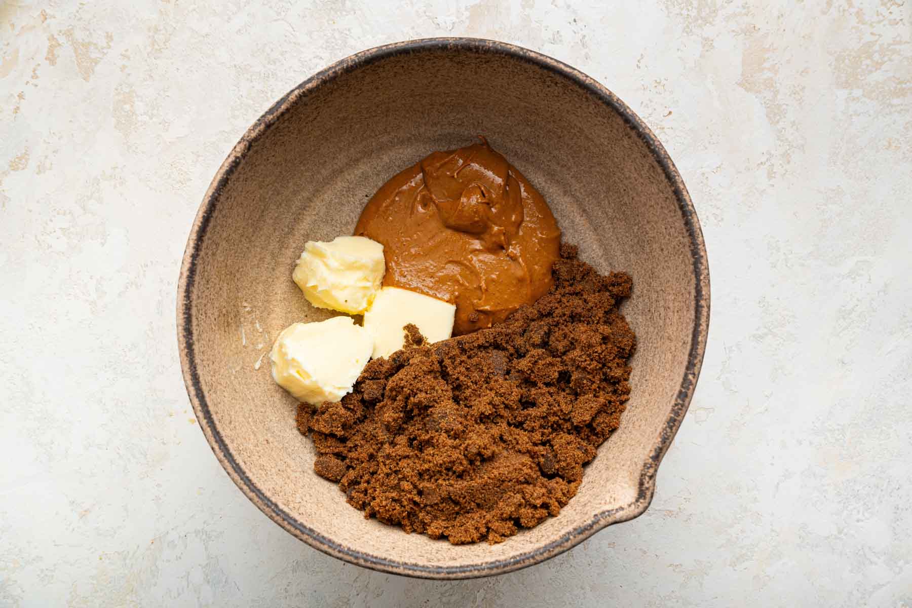 Brown bowl with cubed butter and brown sugar.