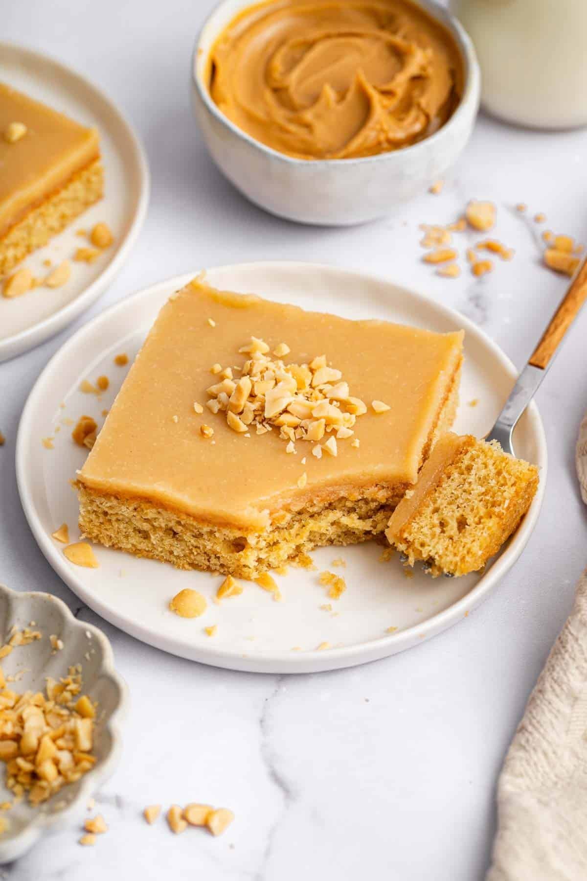Square slice of peanut butter sheet cake on white plate with fork.