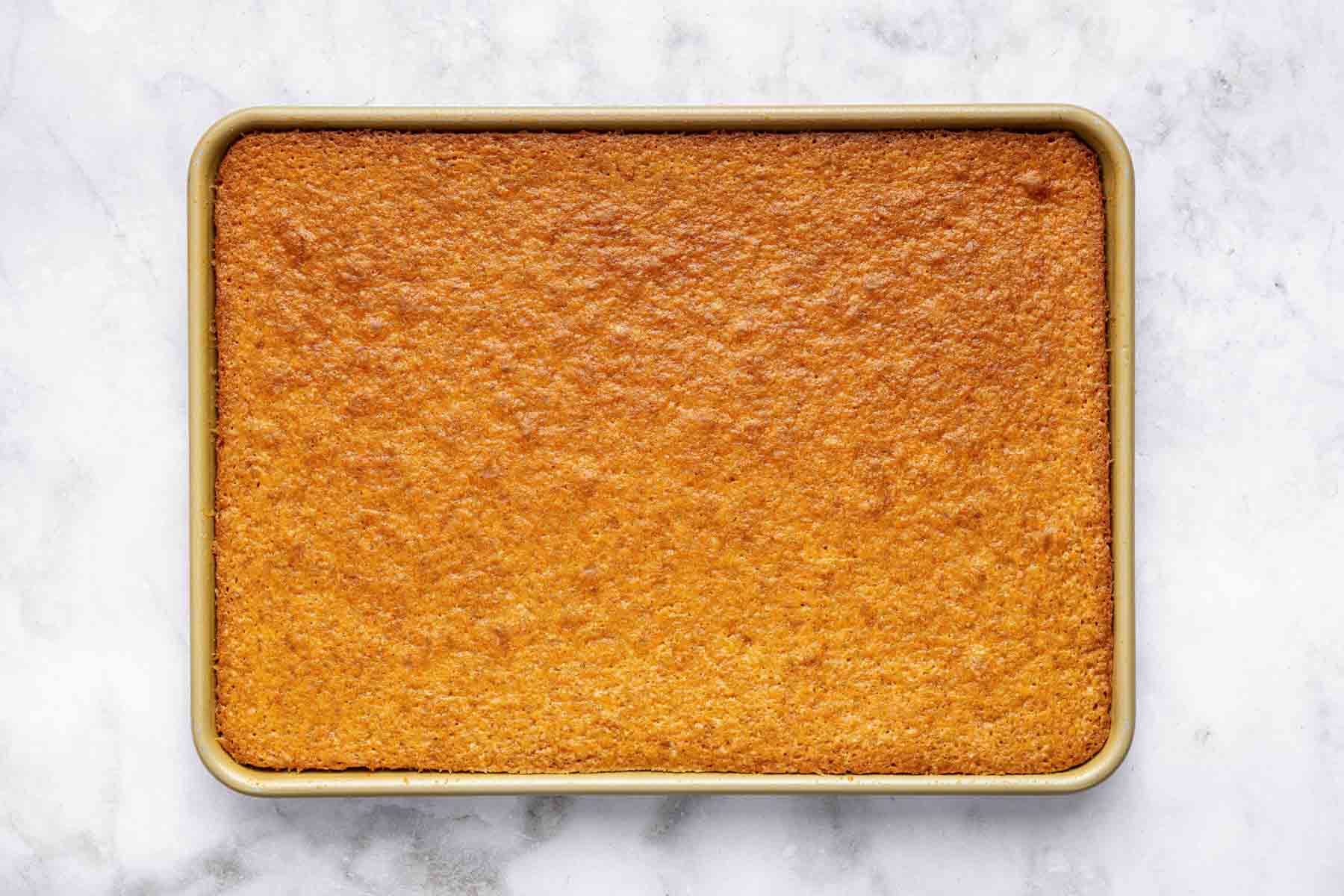 Freshly baked peanut butter sheet cake on marble surface.