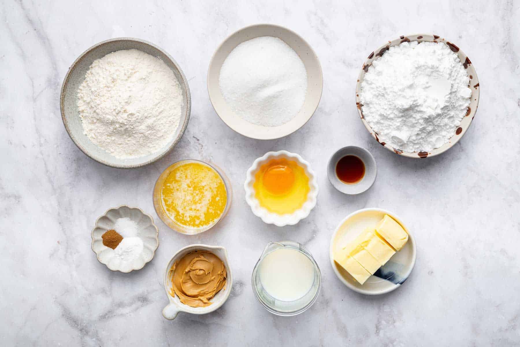 Small white bowls of flour, sugar, and powdered sugar on white counter.
