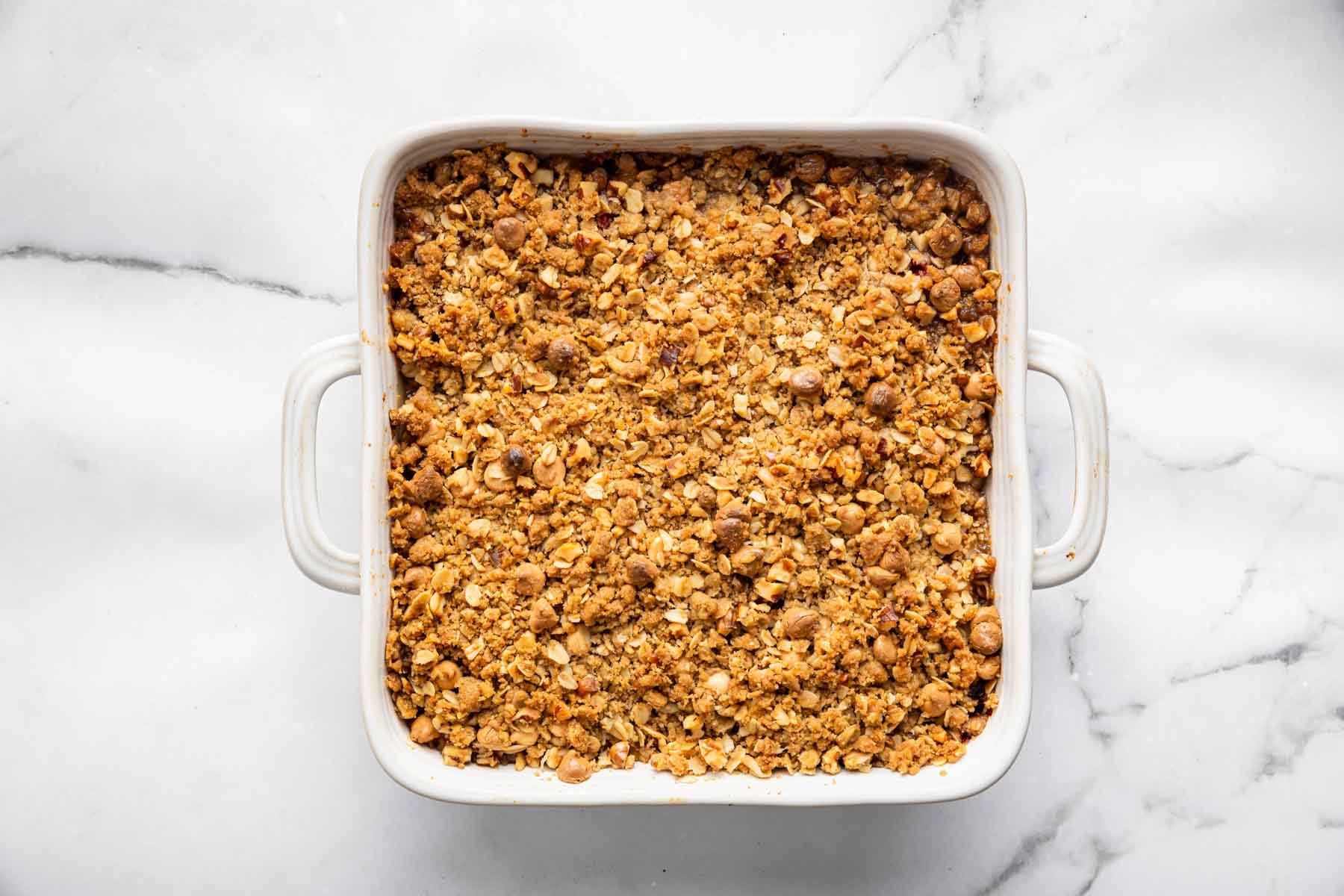 Crispy golden brown fruit dessert in a square white baking dish.