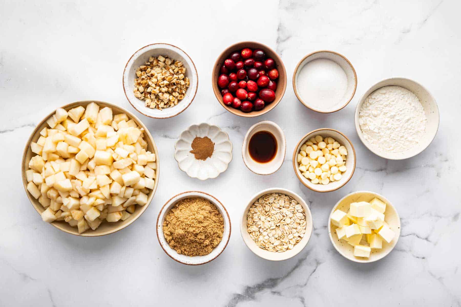 Small bowls of diced fruits, oats, sugars, and butter.