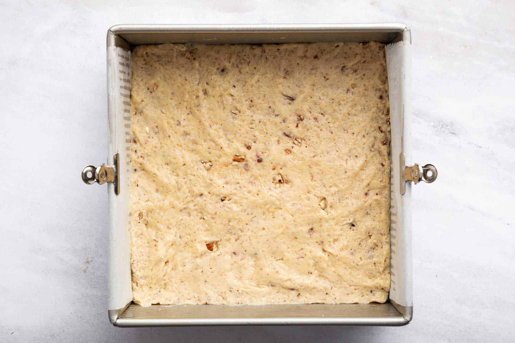Square pan with light brown speckled raw dough in it.