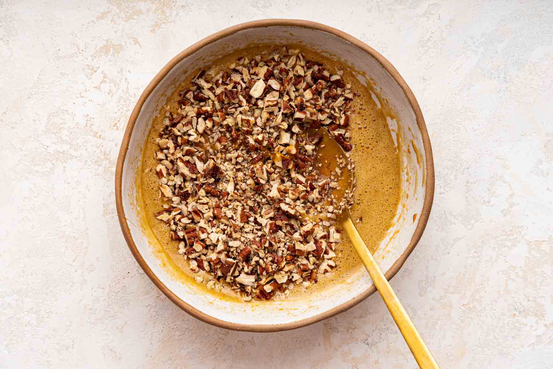 Yellow liquid batter with chopped nuts on top before being stirred in.