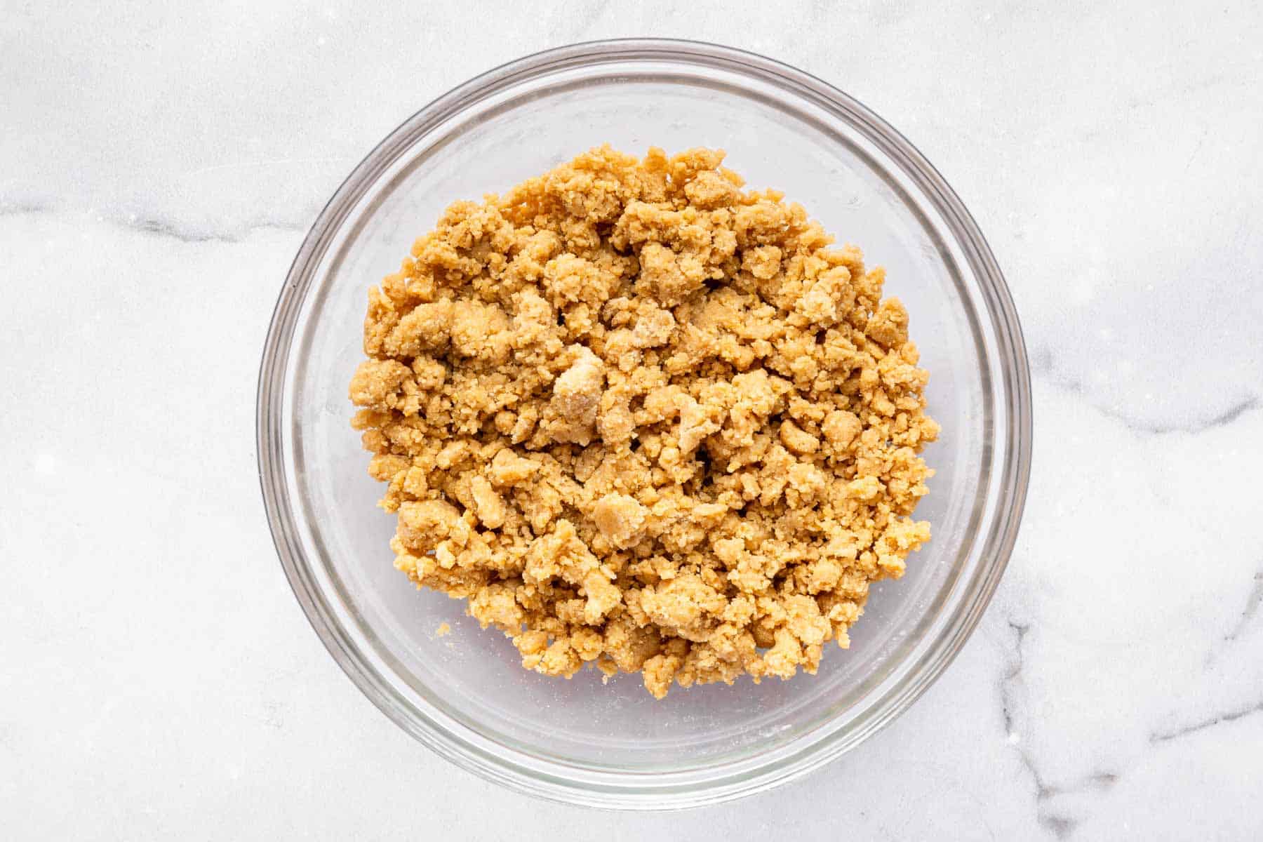 Brown crumble mixture for topping a dessert in glass bowl.