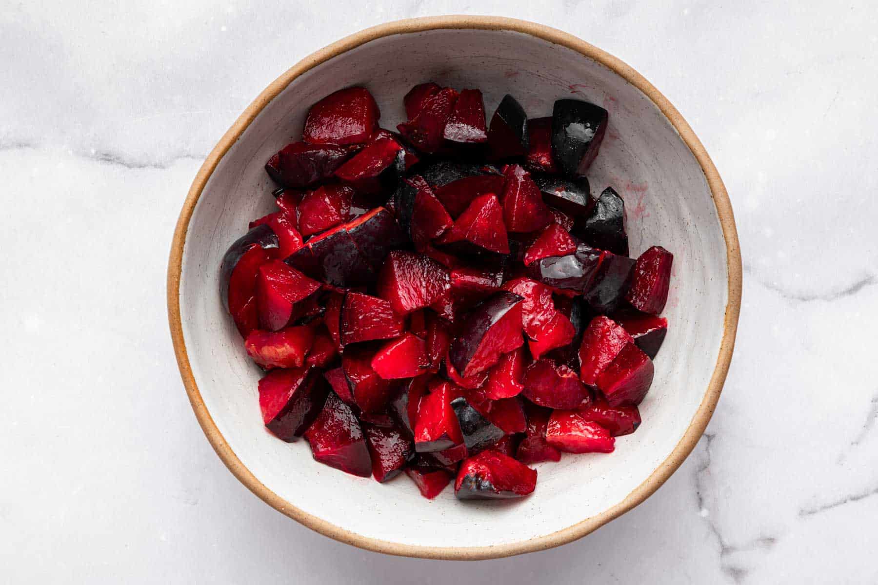 Bowl of Santa Rosa plums sliced in a white bowl.