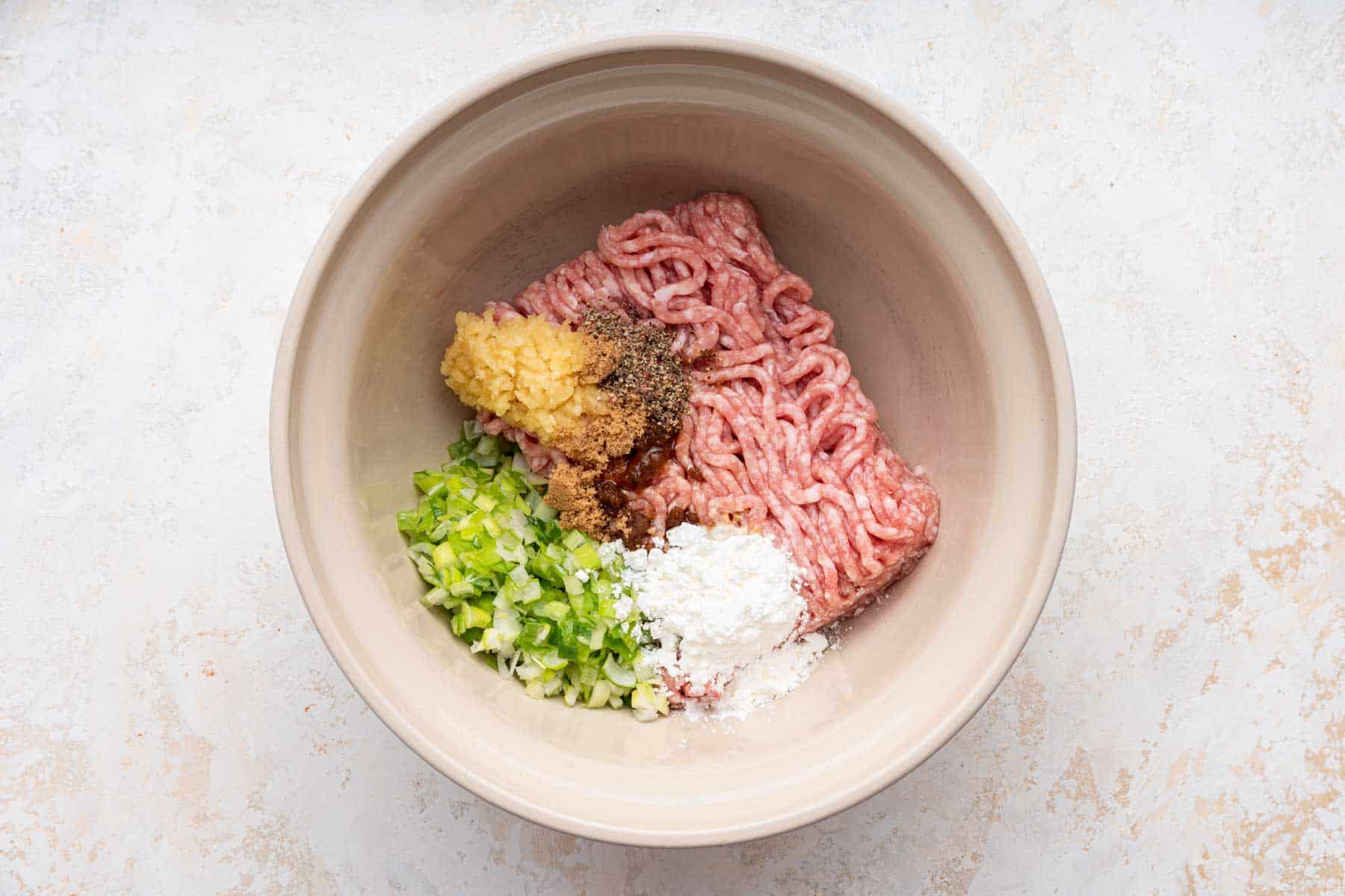 Large bowl with ground pork, scallions, cornstarch and grated garlic.