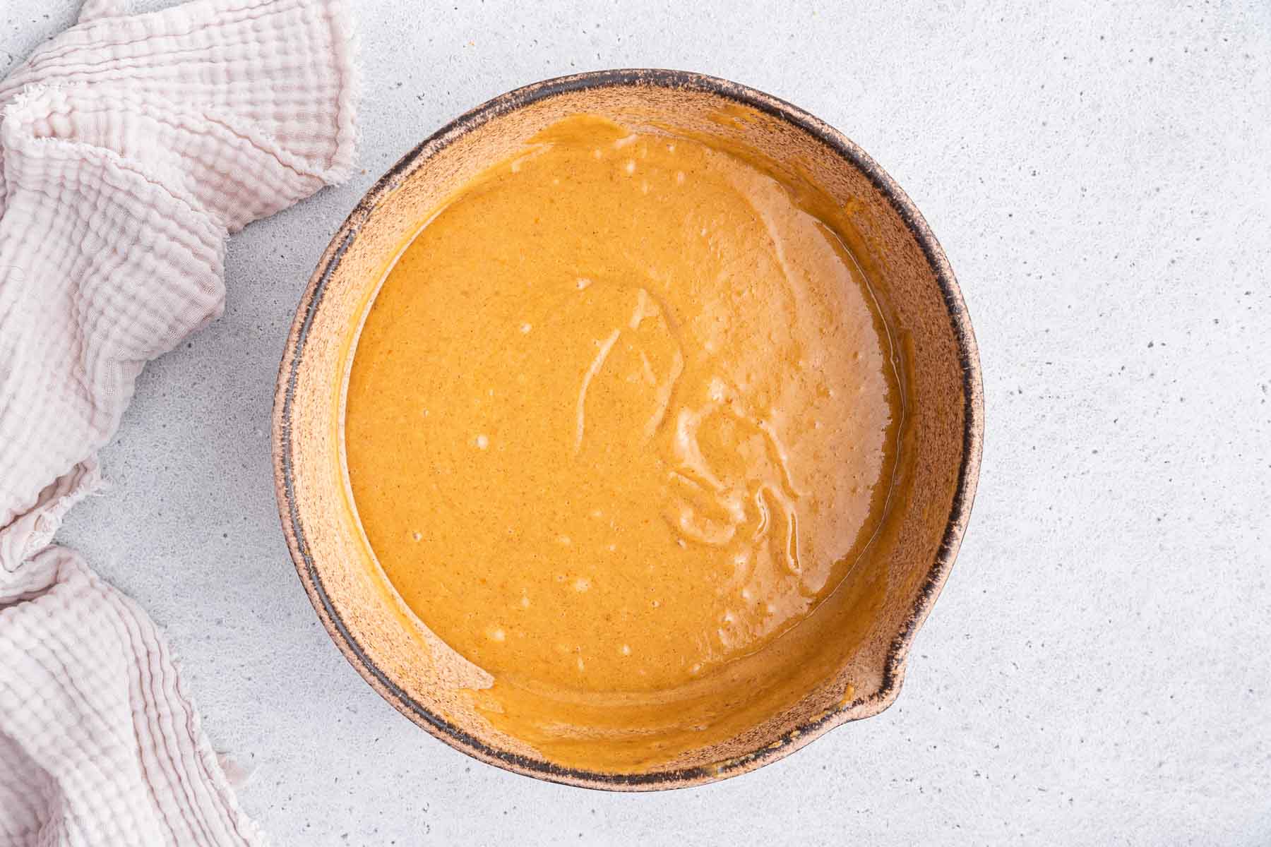 Orange batter in brown earthenware bowl.