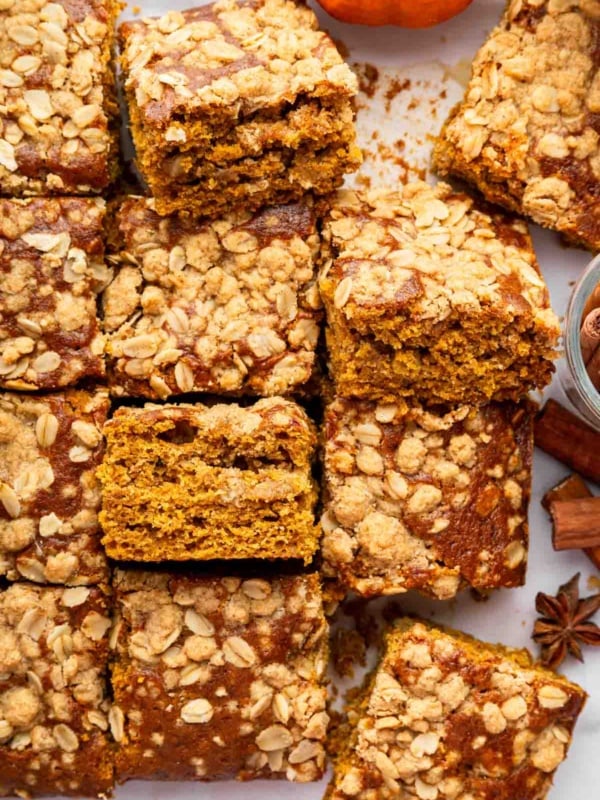 Squares of pumpkin coffee cake on table with a mini pumpkin.