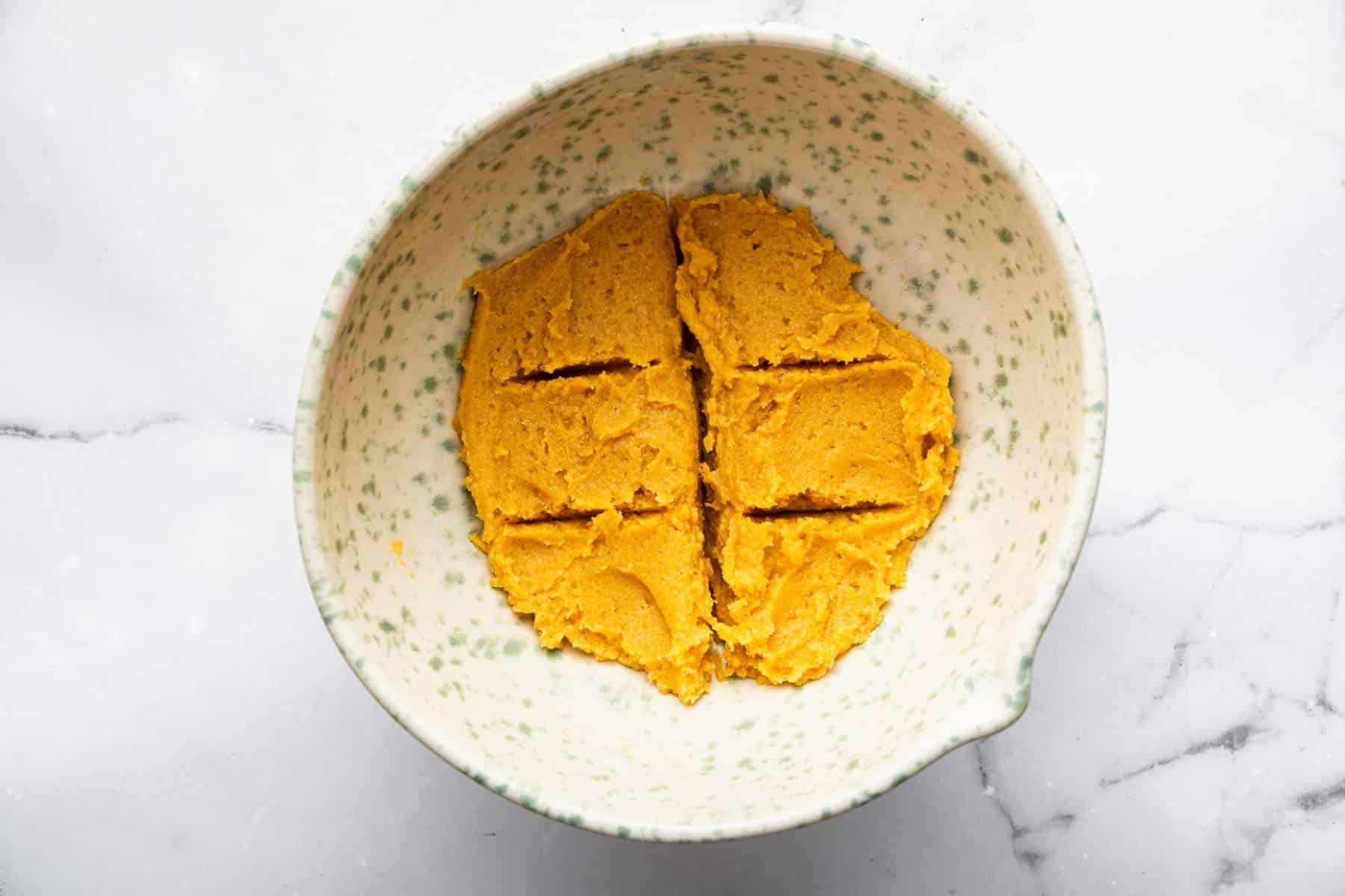 Pumpkin sugar cookie dough in a bowl divided into 6 portions.