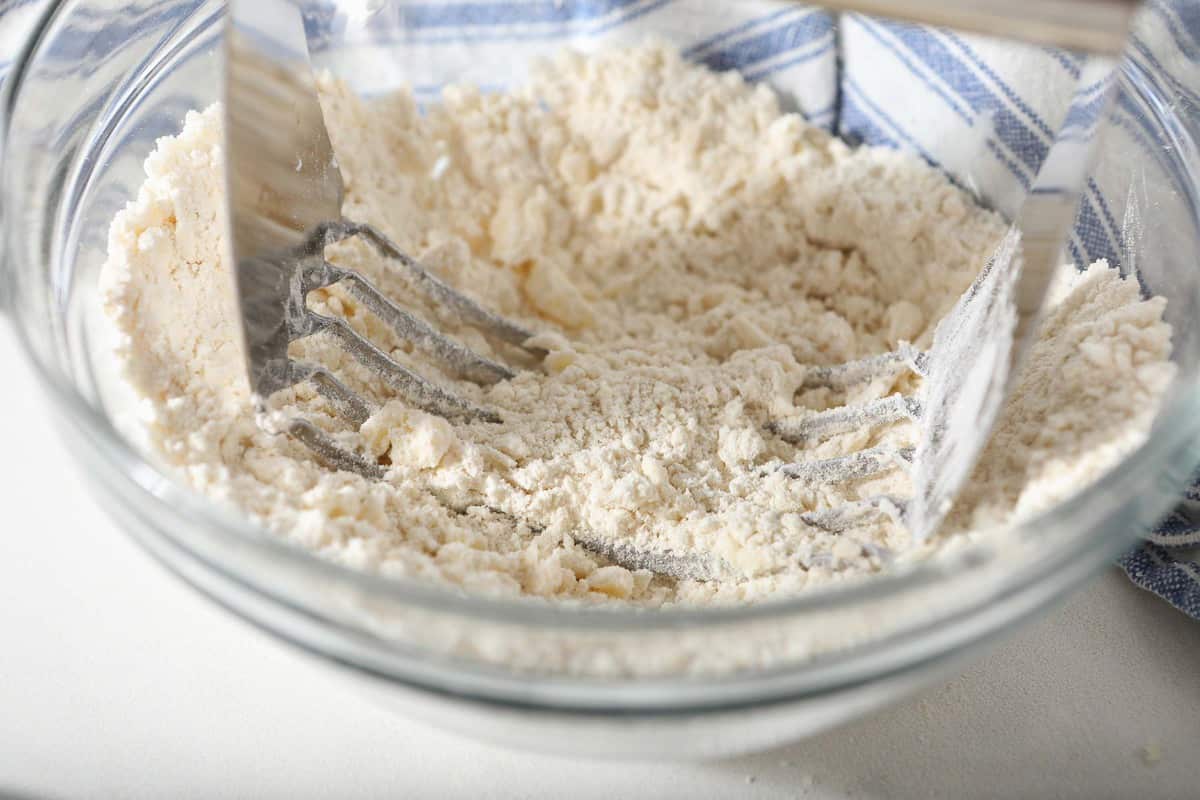 Pastry blender in a bowl with flour and butter.