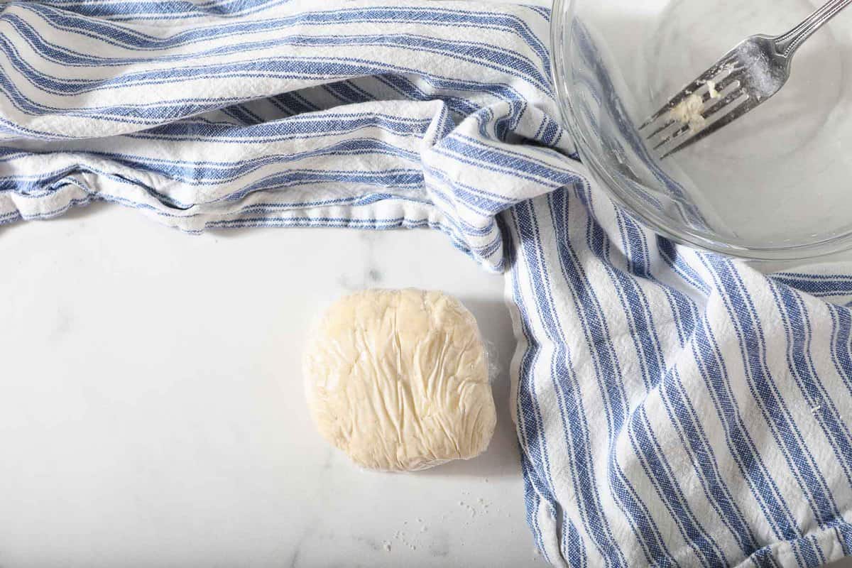 Raw pie dough circle wrapped in plastic wrap.
