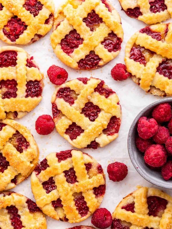Overhead shot of raspberry pie cookies, round circles like mini pies with red berries.