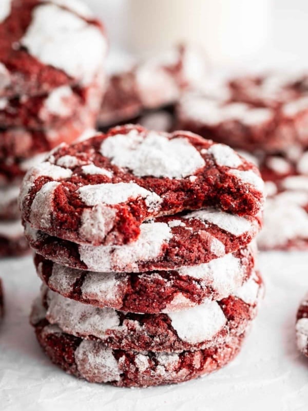 Stack of red velvet crinkle cookies on white surface.